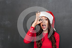 Cheerful brunette woman in red blouse and christmas hat