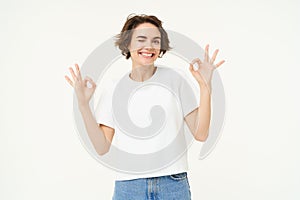 Cheerful brunette woman shows okay, ok sign and smiling, gives her approval, recommanding, saying yes, zero problem