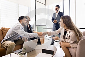 Cheerful business colleagues shaking hands at diverse business team meeting