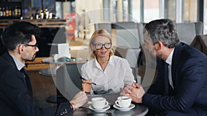 Cheerful business lady negotiating agreement with male partners meeting in cafe