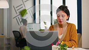 Cheerful business lady typing on laptop computer and smiling sitting at desk