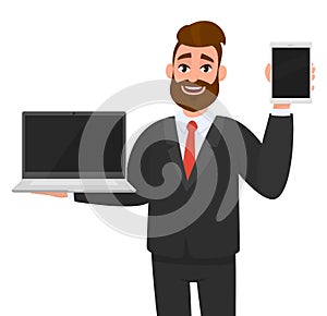 Cheerful business man holding or showing a latest brand, empty screen laptop computer PC and tab, tablet, pad in hand.