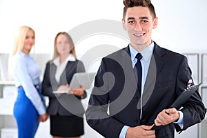 Cheerful business man in office with colleagues in the background, sturt-up team