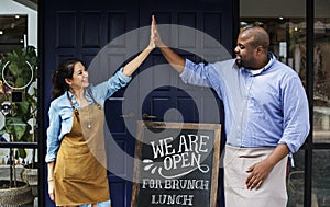 Cheerful business owners standing with open blackboard