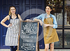 Cheerful business owners standing with open blackboard