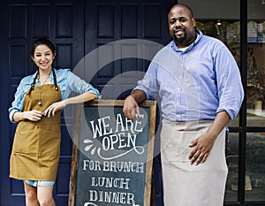 Cheerful business owners standing with open blackboard photo