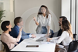 Cheerful business presenter woman talking to creative team of employees