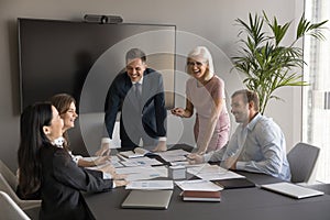 Cheerful business professionals reviewing paper reports on meeting table