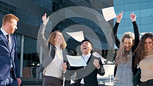 Cheerful business team throwing papers up in the air celebrating success.