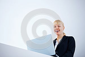 Cheerful business woman working on laptop. Business woman smiling and working on laptop - copyspace.