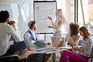 Cheerful business woman showing stats on whiteboard to coworkers. business, meeting, briefing concept