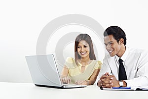 Cheerful businessman and businesswoman working on laptop together. Conceptual image