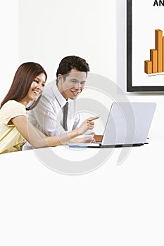 Cheerful businessman and businesswoman working on laptop together. Conceptual image