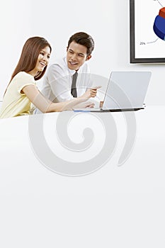 Cheerful businessman and businesswoman working on laptop together. Conceptual image