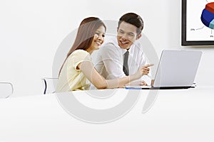 Cheerful businessman and businesswoman working on laptop together. Conceptual image