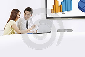 Cheerful businessman and businesswoman working on laptop together. Conceptual image