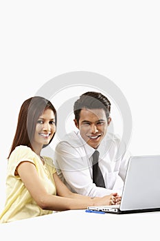 Cheerful businessman and businesswoman working on laptop together. Conceptual image