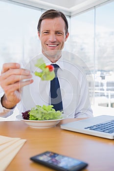 Cheerful businessman eating a salad