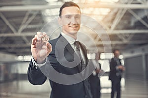 Cheerful businessman holding bitcoin in hand