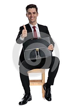 Cheerful businessman holding his briefcase and giving a thumbs up
