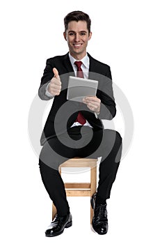 Cheerful businessman holding his tablet and giving a thumbs up