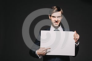 Cheerful businessman pointing with finger at empty board isolated photo