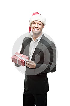 Cheerful businessman in santa hat holding red gift