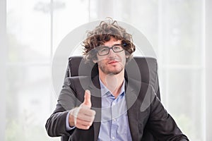 Cheerful businessman showing thumbs up in the office, Young man doing happy thumbs up