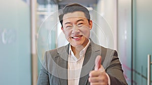 Cheerful businessman showing thumbs up while posing and smiling at camera