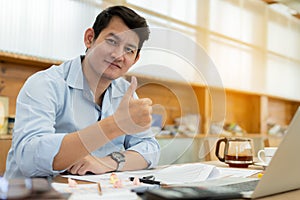 Cheerful businessman showing thumbs up and smiling at camera