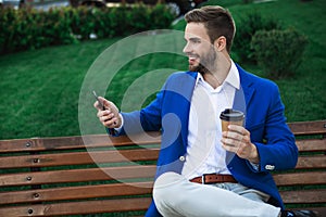 Cheerful businessman sitting on bench outdoor