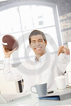 Cheerful businessman throwing football