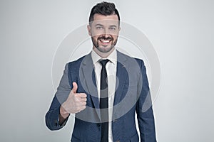 Cheerful businessman thumbs up posing and smiling at camera. dressed in a classic suit. Isolated on a white background