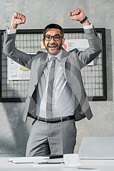cheerful businessman triumphing and smiling at camera