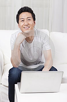 Cheerful businessman using a laptop computer in sofa