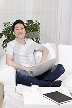 Cheerful businessman using a laptop computer in sofa