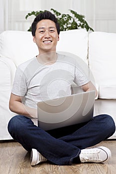 Cheerful businessman using a laptop on the floor