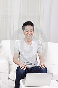 Cheerful businessman using a laptop in sofa