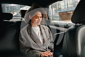 Cheerful businesswoman accountant working on laptop sitting car backseat on the way to office