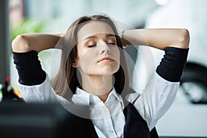 Cheerful businesswoman dreaming at workplace. Female office worker takes break after job done. Business lady relaxing at