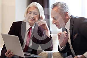 Cheerful businesswoman and her colleague working with the laptop