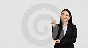 Cheerful businesswoman pointing upwards at free space and smiling