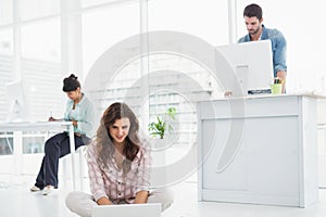 Cheerful businesswoman sitting on the floor using laptop