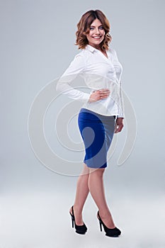 Cheerful businesswoman standing over gray background