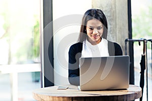 Cheerful businesswoman using laptop in cafe