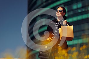 Cheerful Businesswoman Wearing Sunglasses Holding a Shopping Bag