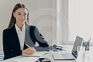 Cheerful bussiness woman sitting at her workplace in office