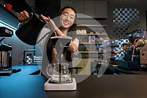 Cheerful cafe worker brewing a caffeinated drink for a client