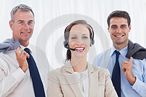 Cheerful call center agent posing with her work team