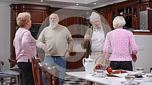 Cheerful carefree old men and women dancing in living room meeting on weekend. Positive joyful Caucasian couples of